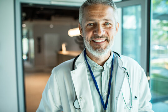 Smiling senior doctor with stethoscope in hospital corridor