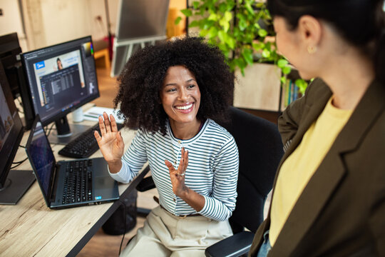 Smiling coworker greeting colleague at modern office desk