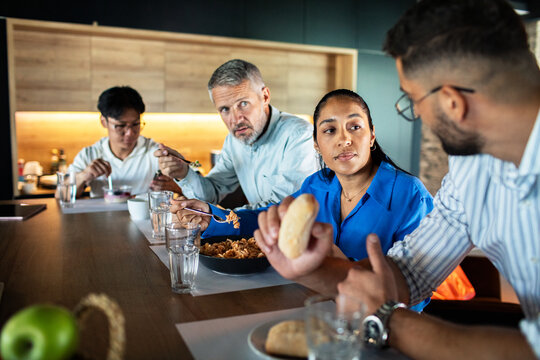Coworkers eating lunch together in office kitchen