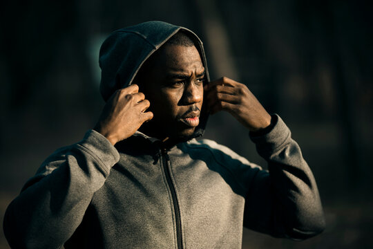 Focused man adjusting hoodie for outdoor run
