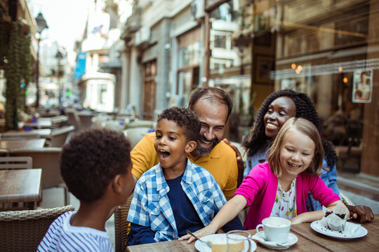 Happy family with children enjoying dessert at outdoor city cafe