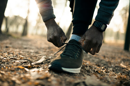 Runner tying running shoes on forest trail at sunrise