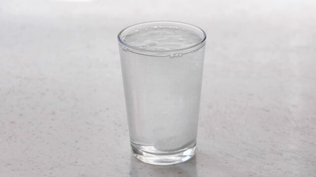 Effervescent tablet dissolving in a glass of water with bubbles