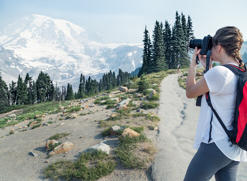 Side view of a Female hiker taking a photo with a camera, Mount Rainier National Park, Washington, USA