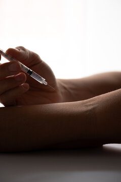 Addict injecting drug dose into forearm vein