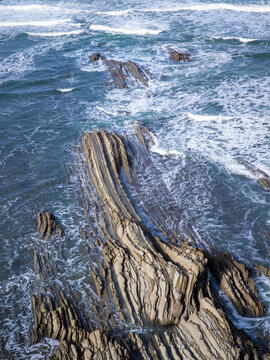 Flysch rock formations meeting ocean waves at coast
