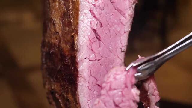 A tight, detailed shot captures a sharp chef's knife making a clean cut into a succulent, medium-rare picanha steak (also known as a rump cap or sirloin cap). The rich red interior and the texture of 