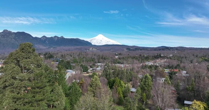 Toma a&eacute;rea de la ciudad de Puc&oacute;n con fondo del volc&aacute;n Villarrica en d&iacute;a soleado en el sur de Chile