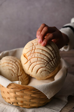 Close-up of a person grabbing a Mexican artisan bread from a basket. Food photography low key