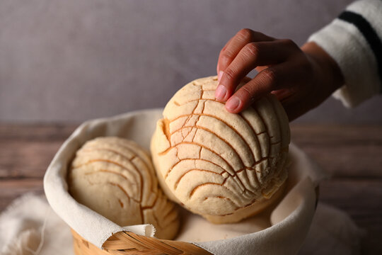 Woman's hand picking a traditional Mexican sweet concha bread, Concha from a basket. Food photography low key