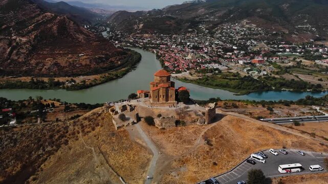 Aerial view of jvari monastery near mtskheta confluence filmed by drone at day time. Hilltop church is overlooking winding kura and aragvi rivers nearby village with panoramic Caucasus ridges