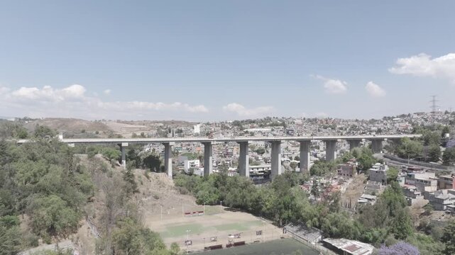 Aerial drone flying forward towards elevated highway bridge over urban sprawl and valley in Atizap&aacute;n, Estado de M&eacute;xico. Shot in D-Log M