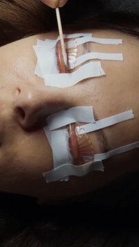 Woman receiving a lash lift. An aesthetic procedure where an aesthetician applies perming solution to her natural eyelashes. Carefully preparing and treating them for a more lifted and voluminous look