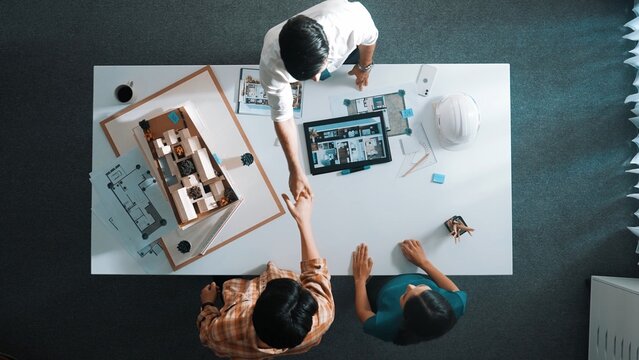 Top down view of civil architect looking at project plan while present to investor at meeting table. Aerial view of skilled designer explain about construction to business people listen. Alimentation.