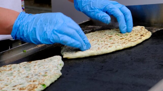 Cook hands in gloves bake flatbread with filling of fresh greens jingyalov hats or lobiani phlovani gozleme kuku sabzi or kutaby with greens. Traditional unique dish fully vegetarian.