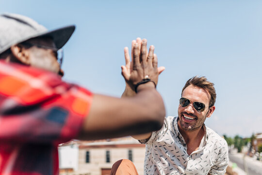 Friends giving high five outdoors on a sunny day