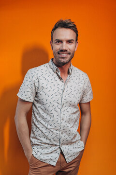 Smiling young man posing against orange studio backdrop