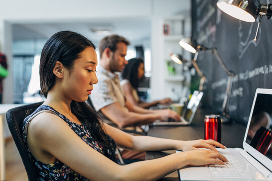 Focused team working on laptops in modern office space