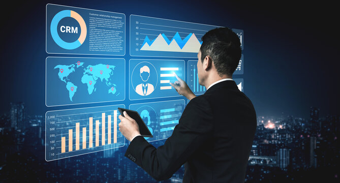 A business executive analyzes data on a digital screen in a modern office setting at night, offering insights into performance and management in a vibrant city backdrop. Ledger