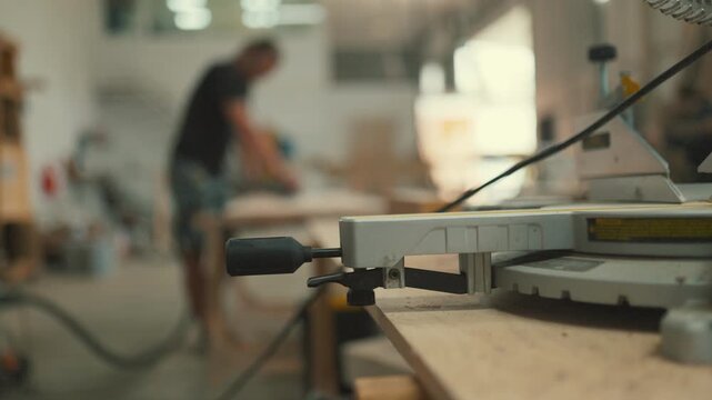 Carpenter working on wood in a workshop with a miter saw