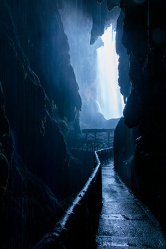 Dark cave leading to powerful waterfall and blue light