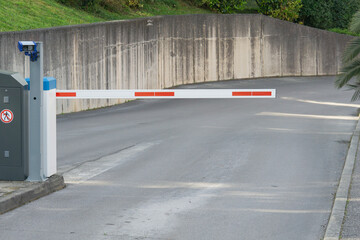 parking barrier gate automatic security white grey industrial street entrance with concrete wall and asphalt road with copy space for banner design concept of transportation, security, logistics © Lana Pietukhova