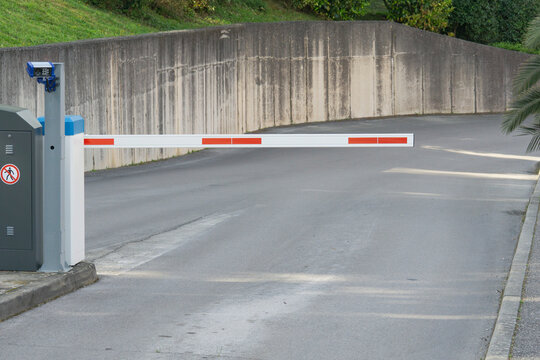 parking barrier gate automatic security white grey industrial street entrance with concrete wall and asphalt road with copy space for banner design concept of transportation, security, logistics