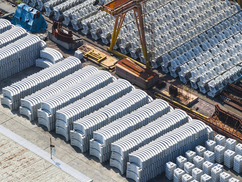 Aerial view of rows of stacked concrete tunnel segments and a large orange gantry crane at an industrial site Taiwan.