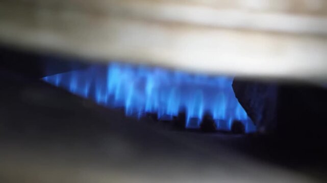 A detailed macro shot showing the steady, bright blue flames of a natural gas burner on a kitchen stovetop. The footage captures the consistent burn and heat of a domestic gas range, highlighting ener