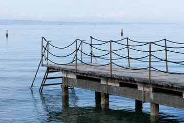 Naklejka premium wooden pier bridge blue calm water surface rope railing sea horizon cloudy atmosphere background with copy space for banner design concept of travel, tourism, architecture