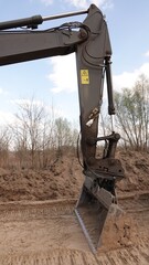 Precyzyjne roboty ziemne koparką gąsienicową: zbliżenie na łyżkę i ramię maszyny budowlanej podczas niwelacji terenu na profesjonalnym placu budowy © tomo81