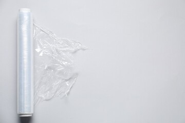 Naklejka premium Roll of cling film on light background, top view. Space for text
