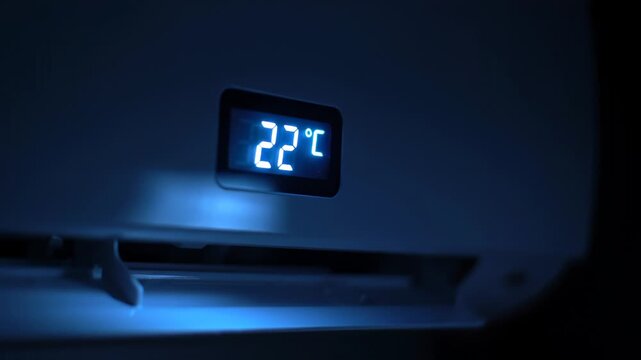Close-up of a digital air conditioner display showing 22 degrees Celsius in a dark room.