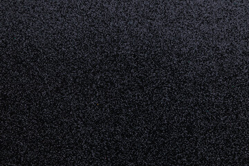 Fototapeta premium Black texture with small particles seen in close view during an indoor setting in bright light