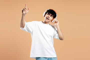 Fototapeta premium Young man listening music pointing finger up expressing joy