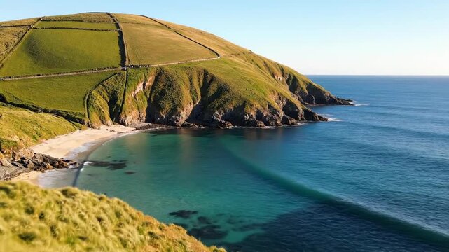 Rolling green mountains meeting a calm blue ocean beside stone walled fields, grassy headland and coastal curves forming a peaceful pastoral shoreline with expansive sea views and clean light