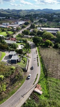 Vista superior de &aacute;rea rural em Bento Gon&ccedil;alves, com casas, vegeta&ccedil;&atilde;o, cultivos, estradas e colinas compondo uma paisagem t&iacute;pica da produ&ccedil;&atilde;o vin&iacute;cola ga&uacute;cha.