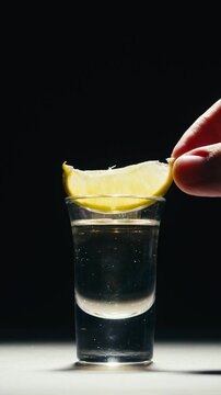 Mexican Tequila Mezcal pouring with lime and salt on a stone table. Strong vodka rum alcoholic drink is poured from a bottle into a shots.