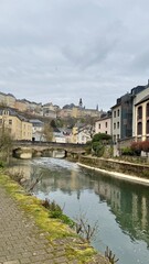 Fototapeta premium Scenic River View of Luxembourg's Old Town with Rainbow Buildings and Stone Bridge
