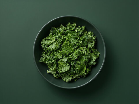 Top view of fresh chopped kale in a dark bowl on a dark green background