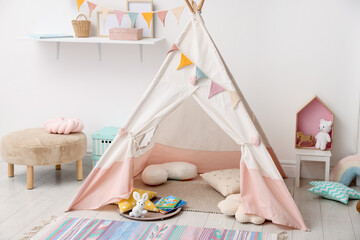 Cute wigwam with pillows, books and toys in stylish child's room © New Africa