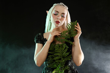 Naklejka premium Beautiful elf girl with floral decor on black background with smoke