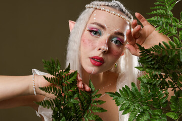 Naklejka premium Beautiful elf girl with floral decor on dark olive background