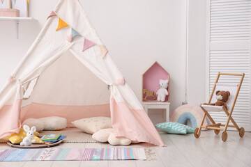 Cute wigwam with pillows, books and toys in stylish child's room. Space for text © New Africa