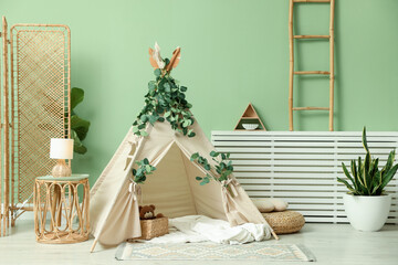 Cute wigwam with leaves and blanket in stylish child's room © New Africa