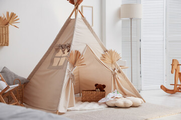 Stylish wigwam with dry leaves in child's room. Space for text © New Africa