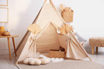 Stylish wigwam with dry leaves in child's room © New Africa