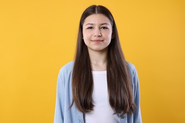 Fototapeta premium Portrait of beautiful teenage girl on orange background