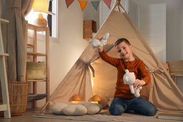 Little boy playing with toys near wigwam at home © New Africa