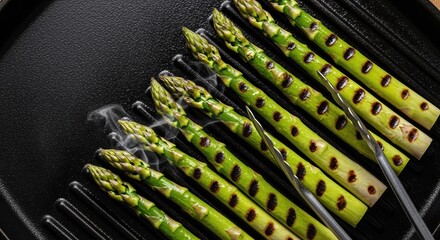 Obraz premium fresh green asparagus grilling with steam on hot cast iron pan in kitchen close up